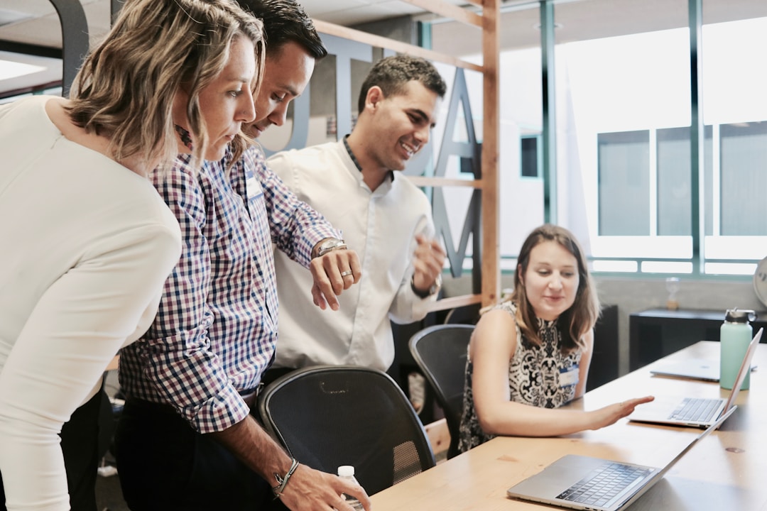 A diverse group of people collaborating around a laptop, focused on knowledgemanagement and innovation strategies.