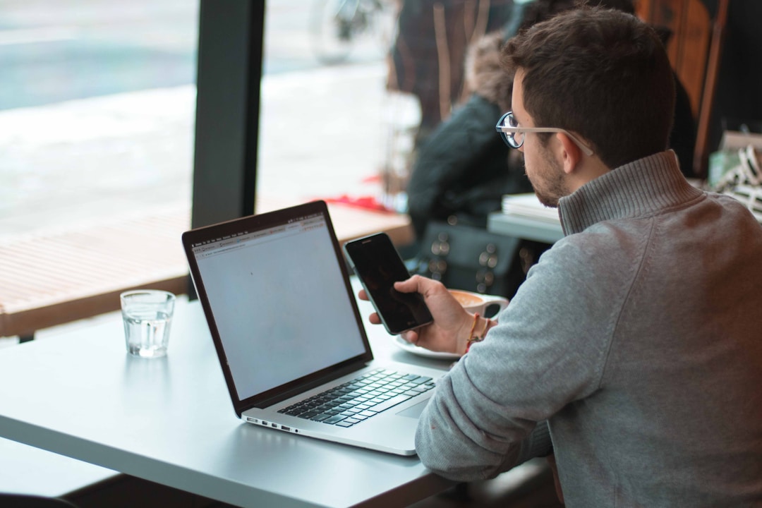 A man at a table using a laptop and cell phone to explore an AI enablement platform.