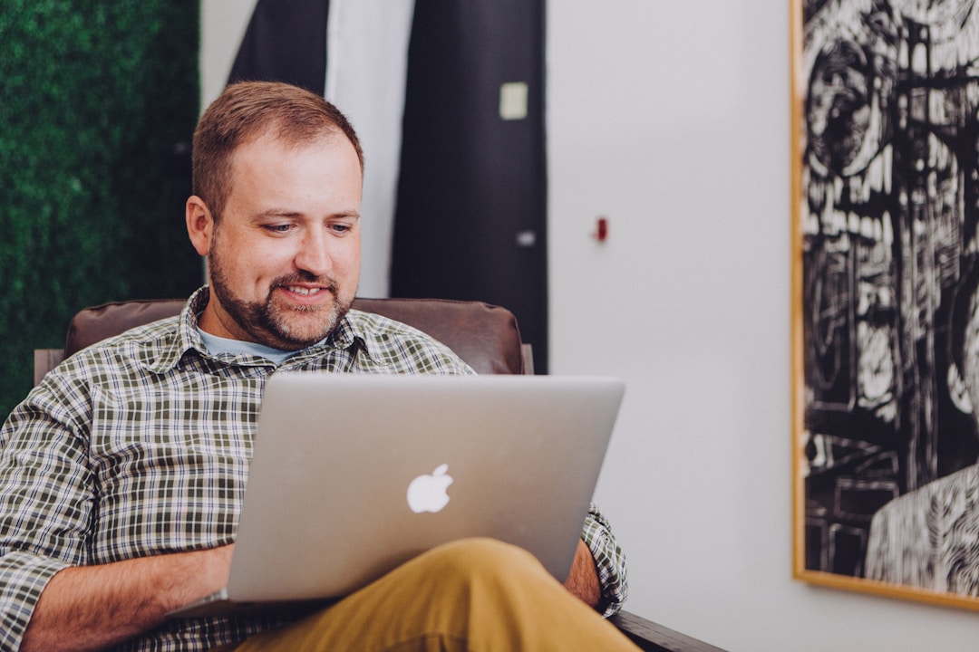 A man seated in an office chair using a laptop, focused on analyzing AI's impact on operational efficiency.